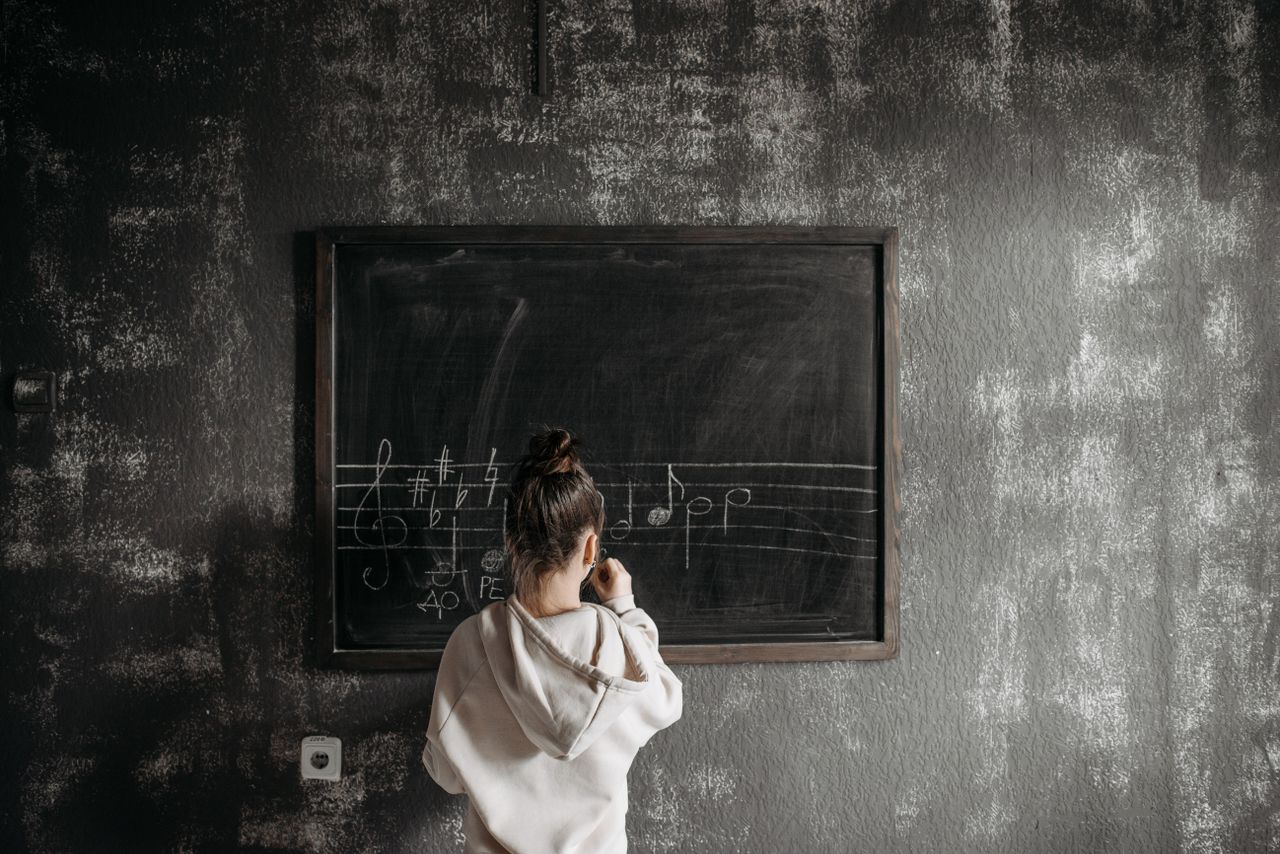 The Art of Drawing Readers In: Your attractive post title goes here A student in a hoodie learns music notation on a chalkboard in class.